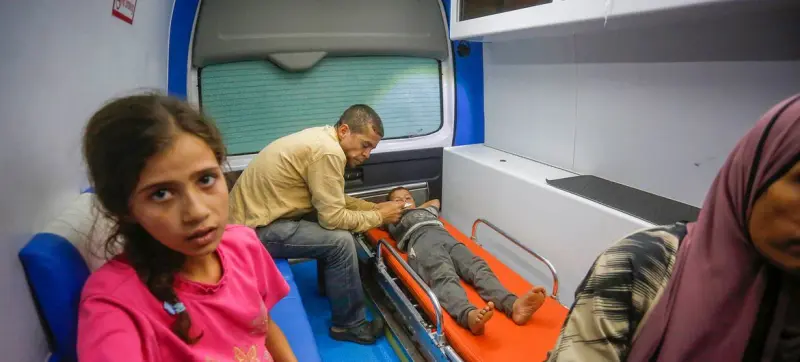 Un niño recibe atención a sus heridas y quemaduras en un patio del hospital Al Aqsa, en la Franja de Gaza. Una comisión de investigación que actúa por mandato del Consejo de Derechos Humanos de las Naciones Unidas acusó a Israel de cometer crímenes de guerra y de lesa humanidad contra los niños en Gaza, Cisjordania y Jerusalén Este. Imagen: Unrwa