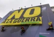 Activistas pacifistas y ambientalistas despliegan, sobre un gran aviso comercial, una pancarta en rechazo a la guerra contra Irán, el pasado marzo en Madrid. Además del costo en vidas y en personas heridas y desplazadas, el conflicto que ya lleva seis meses causa enormes daños materiales, impactos negativos en la economía global, incremento del gasto militar y daños ambientales. Imagen: Greenpeace